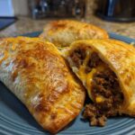 Close-up of golden brown air fryer beef chimichangas, one cut open showing seasoned ground beef and melted cheese filling.
