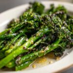 Close-up of bright green, roasted broccolini stalks seasoned with garlic and grated cheese.