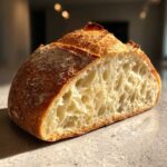 Close-up of a freshly baked french bread loaf cut in half, showcasing a light, airy interior crumb structure.