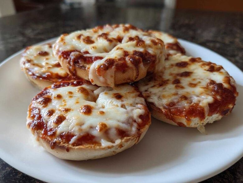 A plate of freshly made pizza bagels topped with melted, bubbly mozzarella cheese and tomato sauce.