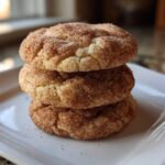 A vertical stack of three soft, chewy snickerdoodle cookies generously coated in cinnamon sugar.