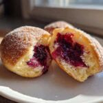 One of the Blueberry Pie Bombs cut in half revealing a rich, dark purple blueberry filling inside the fluffy dough.