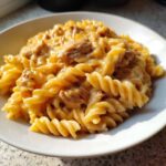 Close-up of a white bowl filled with creamy, cheesy chicken pasta made with fusilli noodles.