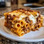 Close-up of a hearty portion of baked ziti style pasta bake with rich meat sauce and melted cheese topping.