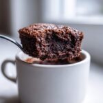 A spoonful of moist, rich chocolate Cottage Cheese Microwave Brownie being lifted from a white mug.