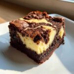Close-up of a rich, fudgy slice of cream cheese brownies with a distinct cream cheese swirl.
