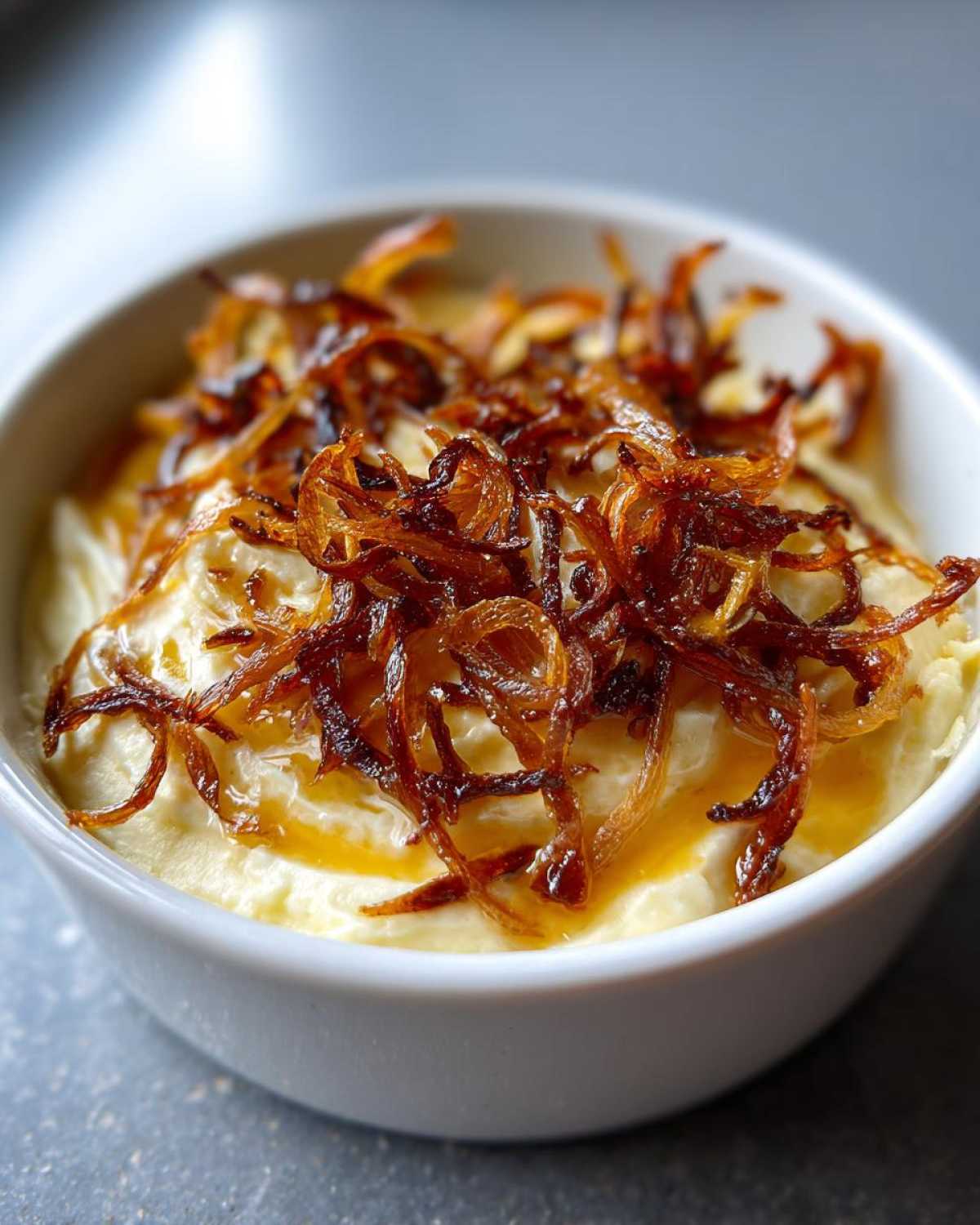 Close-up of creamy caramelized onion dip topped generously with crispy, dark brown fried onions.