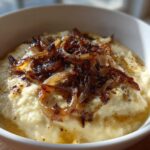 Close-up of creamy caramelized onion dip topped generously with dark, crispy caramelized onions.