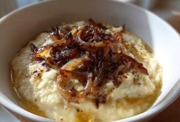 Close-up of creamy caramelized onion dip topped generously with dark, crispy caramelized onions.