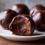 Close-up of a chocolate-dipped Oreo ball with a bite taken out, revealing a rich, fudgy interior.