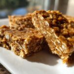 Close-up of several chewy, homemade protein bars made with oats, sitting on a white rectangular plate.