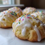 Four soft Italian ricotta cookies drizzled with white glaze and topped with colorful sprinkles.