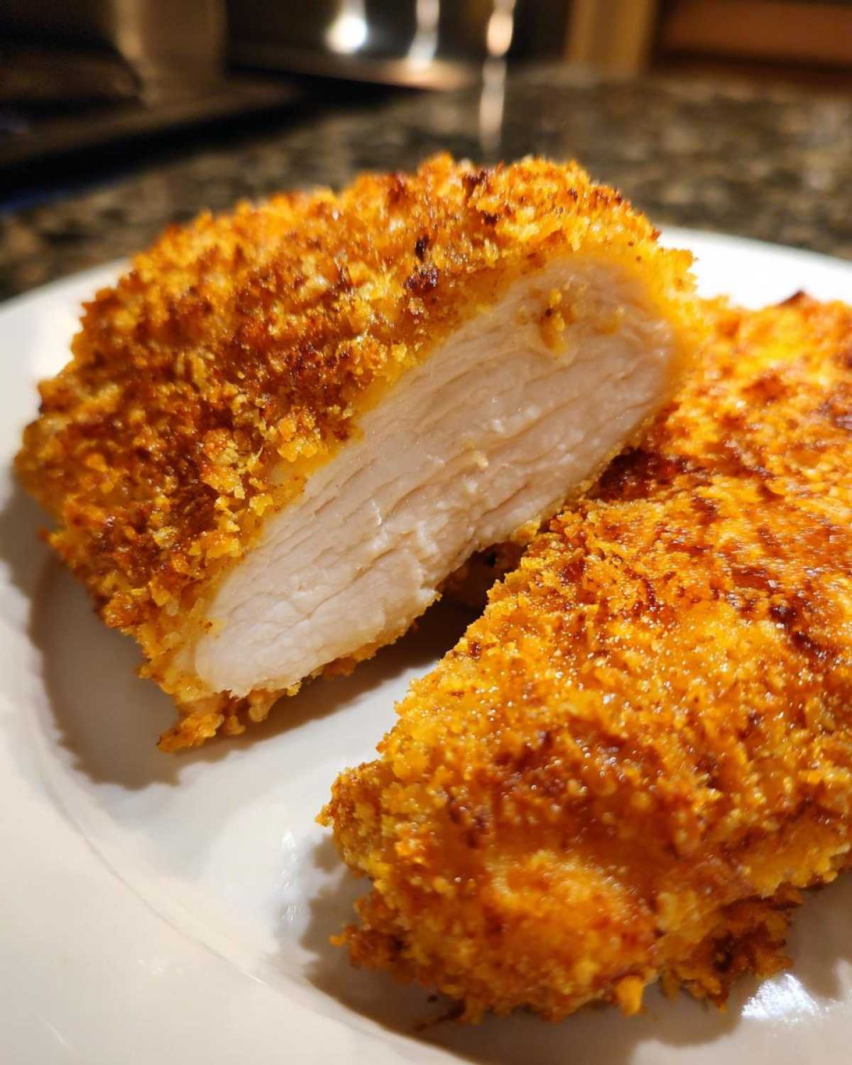 Cross-section of crispy, golden brown air fryer chicken showing the moist, white interior.