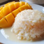 Close-up of delicious mango sticky rice featuring sliced ripe mango next to sweet coconut rice.
