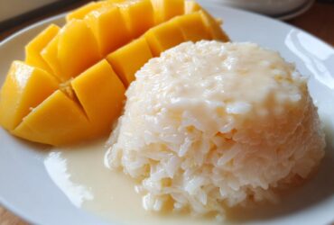 Close-up of delicious mango sticky rice featuring sliced ripe mango next to sweet coconut rice.