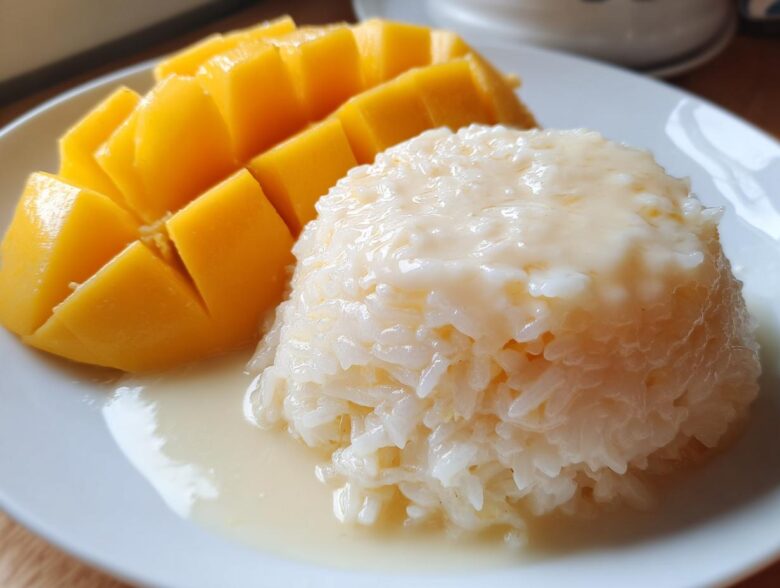 Close-up of delicious mango sticky rice featuring sliced ripe mango next to sweet coconut rice.