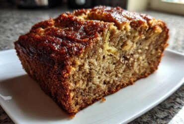 Close-up of a thick slice of moist banana bread recipe with a dark, caramelized crust.