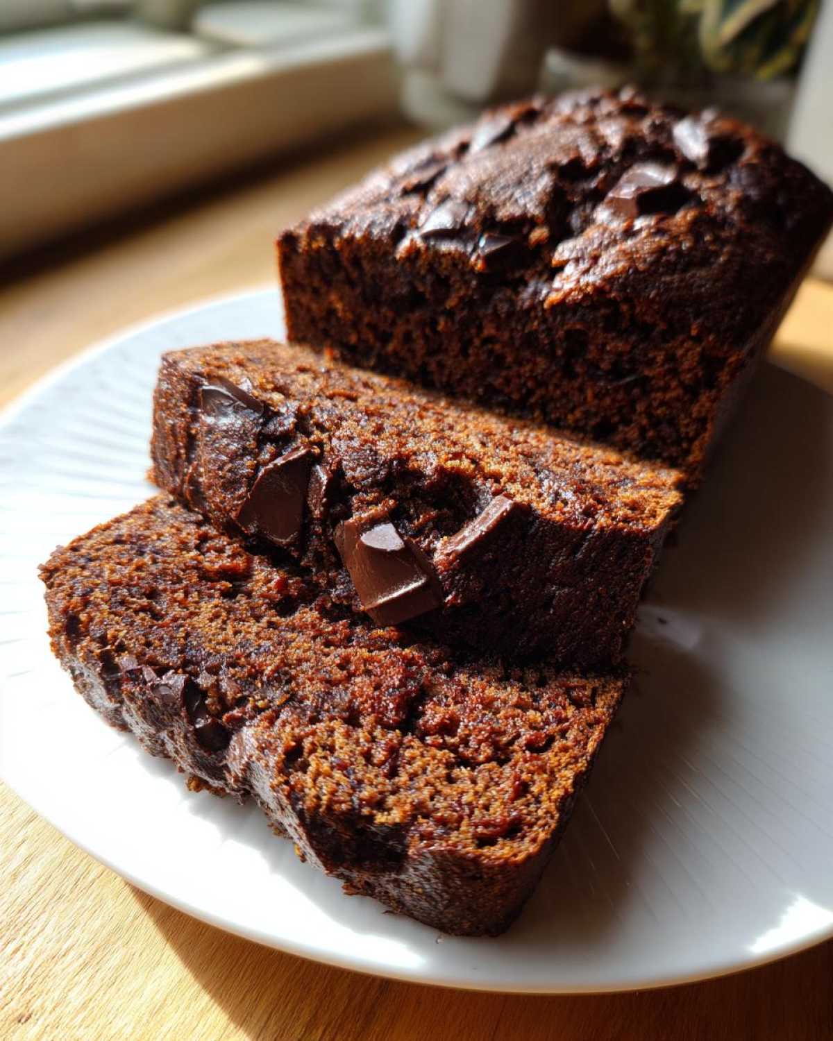 Close-up of moist chocolate banana bread loaf, partially sliced, showing rich texture and chocolate chunks.