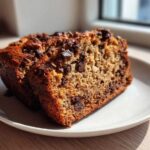Two slices of moist chocolate chip banana bread recipe on a white plate, perfectly baked.