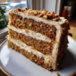 A thick slice of moist, layered spice cake with rich cream cheese frosting and crumb topping.