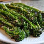Close-up of roasted broccolini spears seasoned with grated cheese, highlighting the char marks.