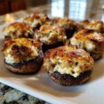 Close-up of several golden brown sausage stuffed mushrooms recipe appetizers served on a white platter.