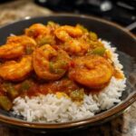 Close-up of a bowl of vibrant Shrimp Creole sauce with plump shrimp and green peppers served over fluffy white rice.