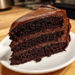 A thick, moist slice of two-layer chocolate cake recipe covered in dark chocolate frosting.