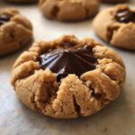 A close-up, tasty shot of a single peanut butter blossom cookie with melted chocolate filling.