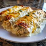 Three delicious white chicken enchiladas covered in melted white and cheddar cheese, garnished with parsley.