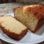 A slice cut from a golden brown, moist loaf of 3-ingredient beer bread resting on a white plate.