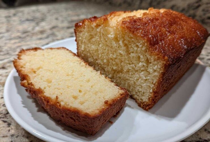 A slice cut from a golden brown, moist loaf of 3-ingredient beer bread resting on a white plate.