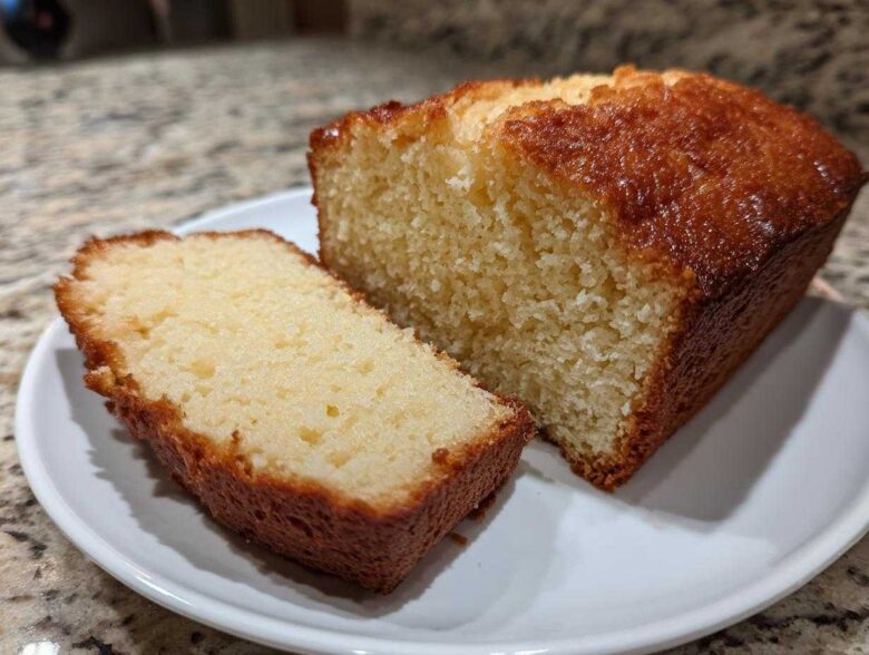 A slice cut from a golden brown, moist loaf of 3-ingredient beer bread resting on a white plate.