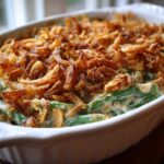 Close-up of a creamy green bean casserole topped generously with crispy fried onions.