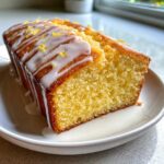 Close-up of a moist slice of lemon pound cake drizzled with white glaze and lemon zest.