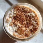 Overhead shot of apple cinnamon overnight oats in a glass jar, topped generously with ground cinnamon.