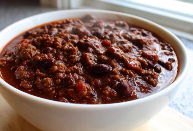 Close-up of a steaming white bowl filled with the best chili recipe, featuring rich ground beef and kidney beans.