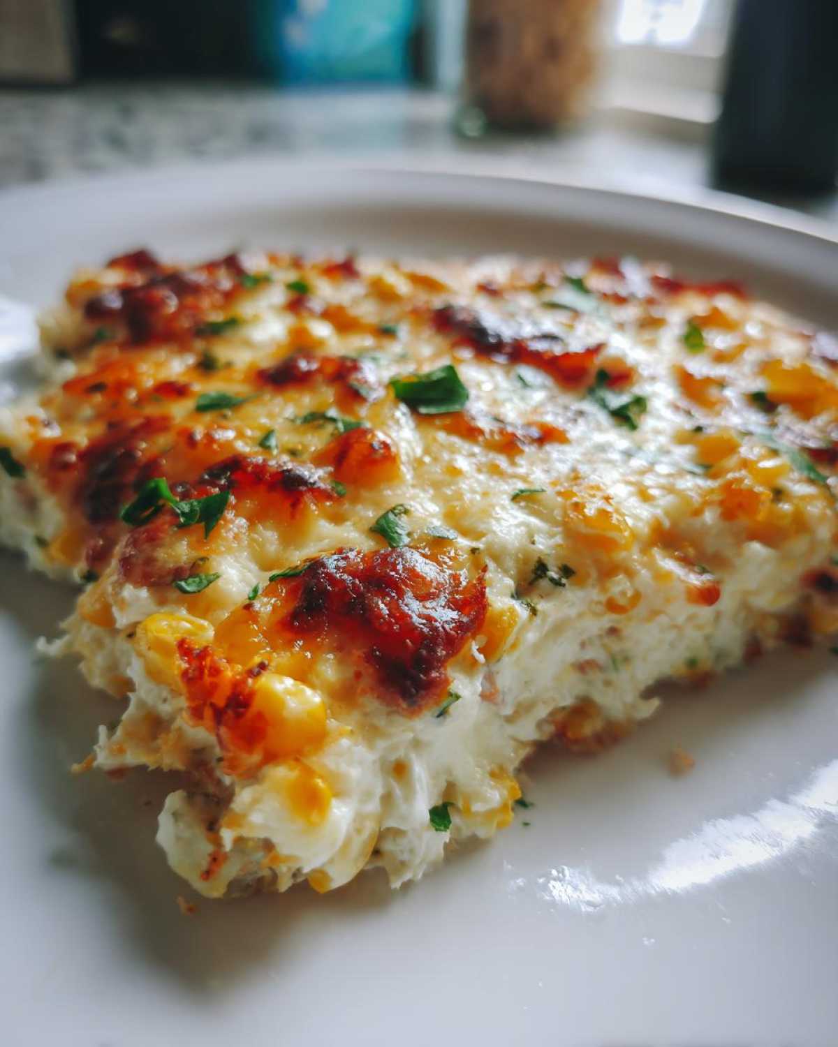 A close-up of a serving of creamy, cheesy street corn dip with a browned top and sprinkled parsley.
