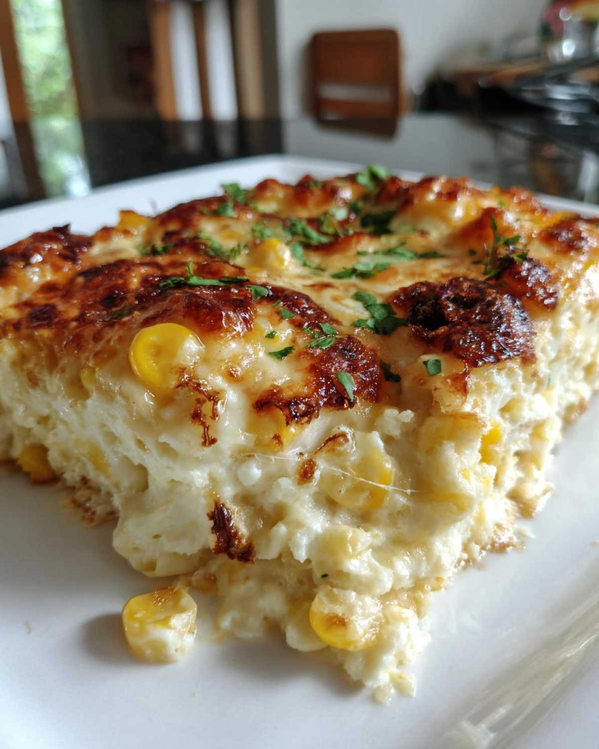 A close-up of a cheesy, baked serving of street corn dip, topped with browned cheese and parsley.