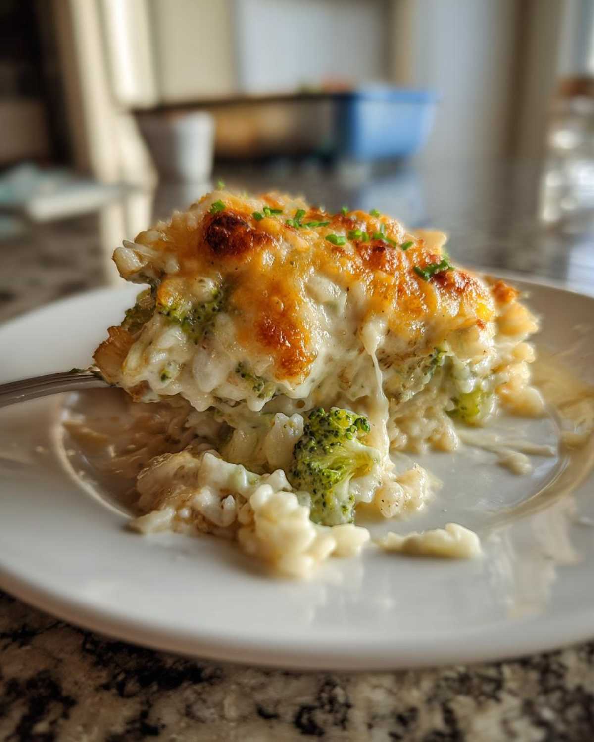 A close-up of a serving of creamy chicken broccoli rice casserole with a golden, bubbly cheese topping.