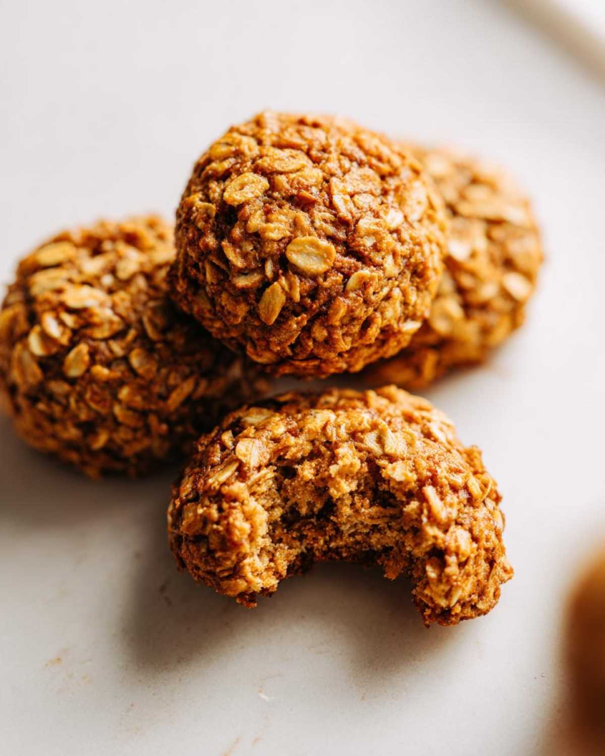Close-up of chewy oatmeal cookies, one with a bite taken out, showing the texture.