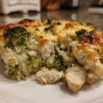 A close-up serving of creamy chicken broccoli rice casserole topped with melted, browned cheese.