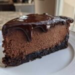 A decadent slice of rich chocolate cheesecake with a dark chocolate crust and glossy ganache topping.