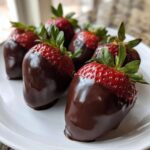 Close-up of several fresh chocolate covered strawberries arranged on a white plate.