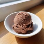 A perfect scoop of rich chocolate protein ice cream served in a small white bowl.