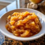 Close-up of chunky, spiced homemade applesauce served in a small white bowl.