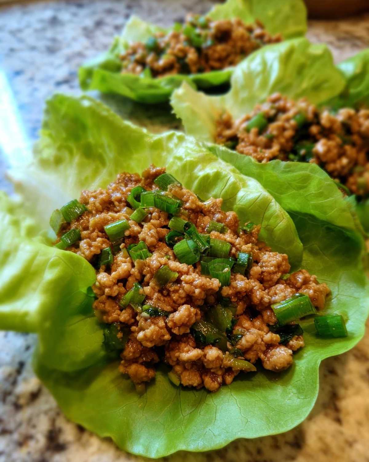 Close-up of delicious chicken lettuce wraps filled with savory ground chicken and topped with fresh green onions.