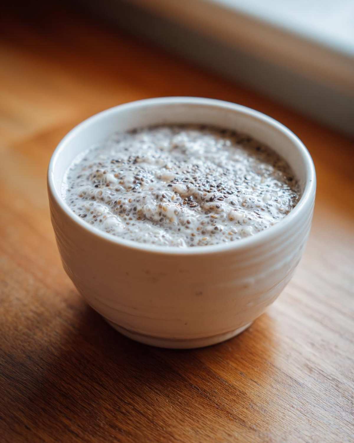 Close-up of creamy coconut chia pudding topped with visible chia seeds in a white bowl.