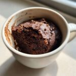 Close-up of a rich, dark chocolate Cottage Cheese Microwave Brownie baked inside a white mug.