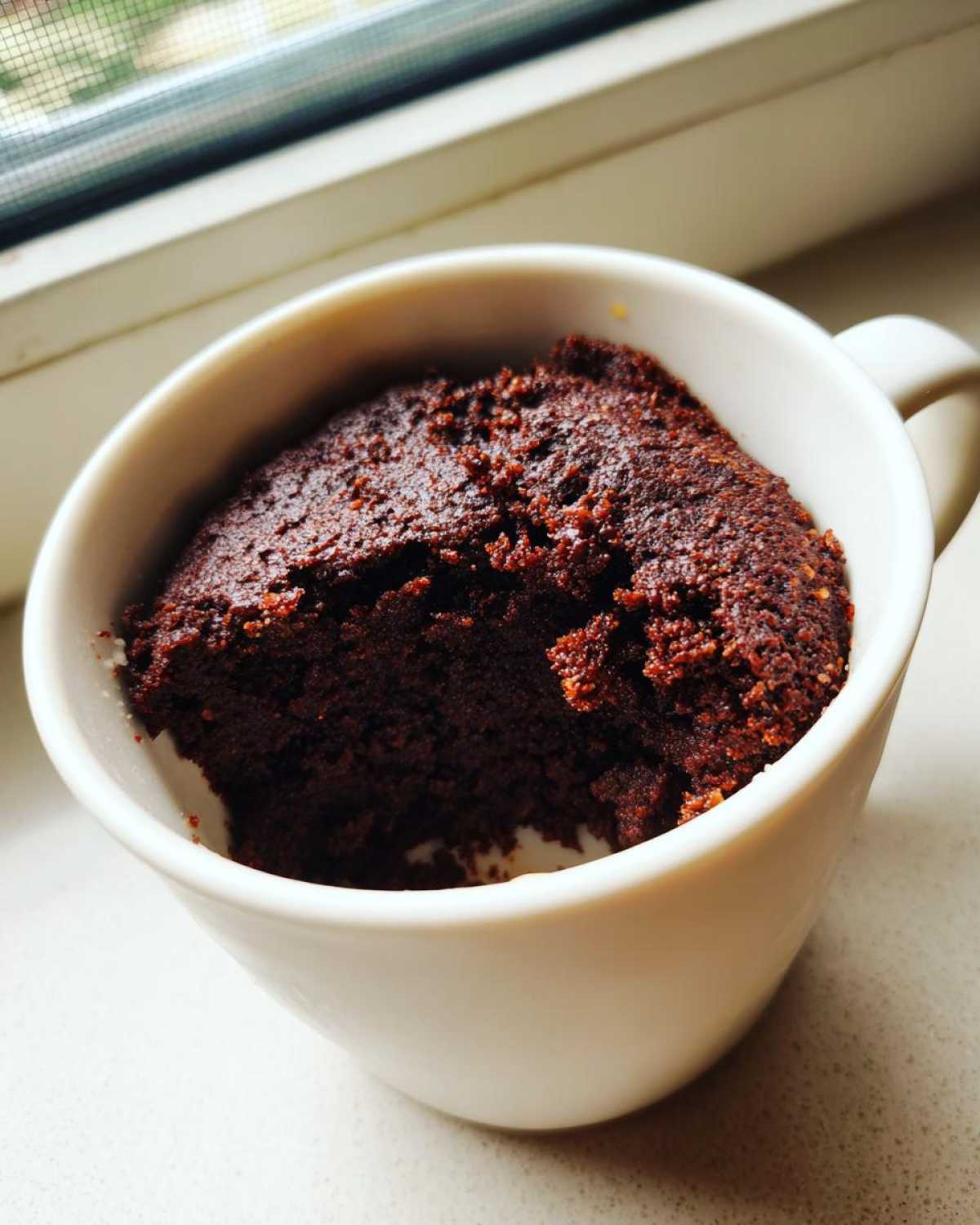 A rich, dark chocolate Cottage Cheese Microwave Brownie baked inside a white mug.